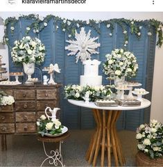 a table topped with white flowers next to a blue wall