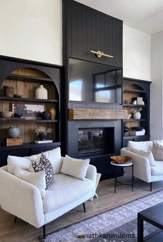 a living room with two white couches and black bookcases on the wall