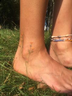 two people standing in the grass with their bare feet covered by bracelets and flowers