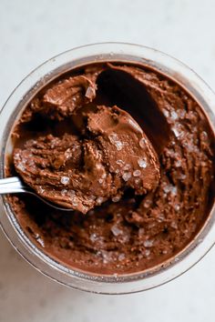 a spoon in a bowl filled with chocolate ice cream on top of a white table