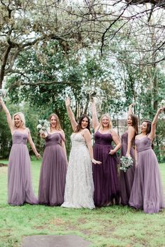 a group of women in long dresses standing next to each other on top of a lush green field