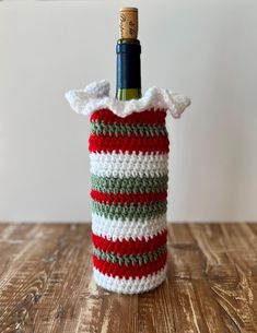 a wine bottle in a crocheted bag with a cork top on a wooden table