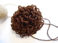 there is a ball of yarn next to a crochet ball on the table