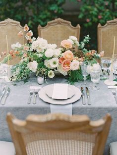 the table is set with white and pink flowers, silverware, and napkins