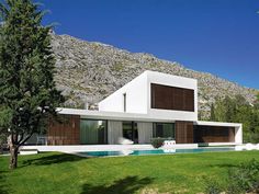 a large white house sitting on top of a lush green field next to a mountain