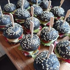 mini sandwiches with toothpicks in them on a wooden board lined with buns