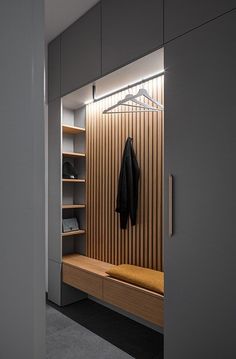 an open closet with a coat hanging on the wall