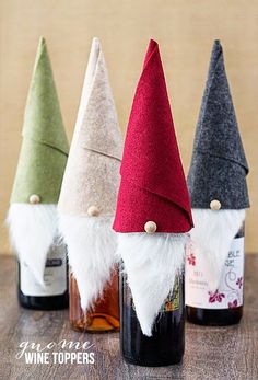 three wine bottles with gnome hats in them