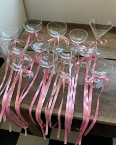 there are many wine glasses with pink ribbons on the table next to eachother