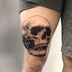 a man's leg with a skull tattoo on the side of his thigh, which is covered in black and white ink