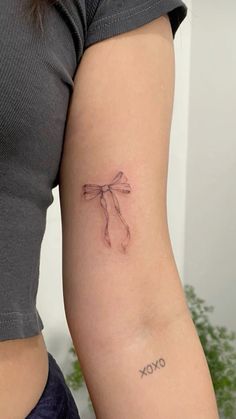 a woman's arm with a tattoo on it that reads xoxo and has a bow