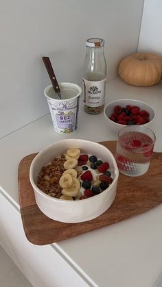 a bowl of fruit and cereal on a cutting board