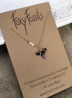 You will fall in love with this natural shark tooth and mini pearl necklace that captures it all in a delicate and dainty design. Each tooth is a fossil dating back millions of years and was hand-collected by Foxy Fossils in Charleston, SC. If you’re looking for the perfect minimalist necklace with a coastal style, look no further. These unique pieces are individually handcrafted by the 2 artisans behind Foxy Fossils. Your purchase not only helps preserve our coastal past but It also helps to pr Dainty Shark Tooth Necklace Smile The Ocean, Sharktooth Jewelry, Shark Tooth Jewelry, Shark Tooth Necklace Diy, Beachy Jewlery, Shark Tooth Necklace Gold, Shark Teeth Jewelry, Shark Jewelry, Sharks Teeth