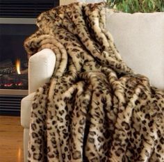 a leopard print blanket sitting on top of a white couch next to a fire place