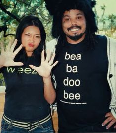 a man and woman posing for the camera with their hands up in front of them