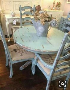 an old table and chairs are painted blue with white trimmings, as well as a bucket full of flowers