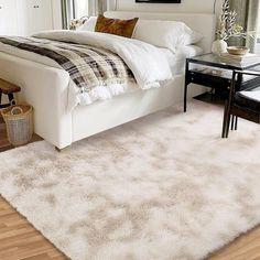 a white bed sitting in a bedroom on top of a hard wood floor next to a window