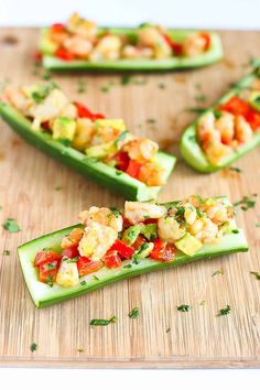 cucumber boats filled with shrimp and vegetables on a wooden cutting board, ready to be eaten