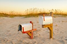 two mailboxes in the sand at sunset