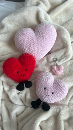 two crocheted hearts are laying on a blanket