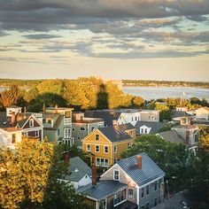 an aerial view of some houses and the ocean in the distance with clouds above them