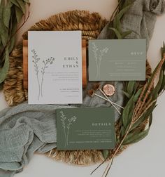 the wedding stationery is laid out with greenery