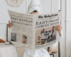 a woman reading a newspaper while sitting at a table with a croissant on her head