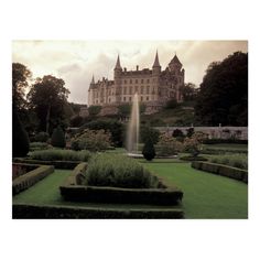 an old castle with a fountain in the middle surrounded by greenery and bushes on a cloudy day