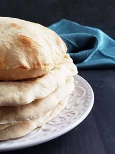 a stack of bread sitting on top of a white plate next to a blue napkin