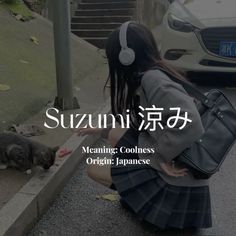 a woman with headphones is petting a cat on the sidewalk in front of her