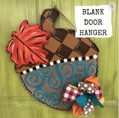 a wooden door hanger with an acorn and plaid bow on it's side