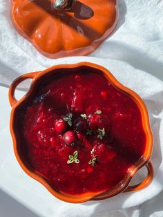 a bowl filled with cranberry sauce on top of a white cloth