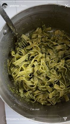 a large metal bowl filled with pasta and pesto