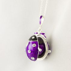 "Bright and festive ladybug locket with heart surprise inside, enameled over solid sterling silver, designed and made in our NJ shop in the tradition of Faberge jewelry. The egg shaped locket ladybug with bright purple wings and a black head, will open to show the red heart inside the locket, steadily fixed in its place. Clear Swarovski crystals are set in the center of the heart, as well as in the dots of the bug and its eyes. The locket is almost 1\"(25 mm) long. You will receive the pendant r Enamel Jewelry For Gifts, Enamel Hallmarked Jewelry For Gifts, Hallmarked Enamel Jewelry For Gifts, Enamel Locket Jewelry For Gifts, Oval Enamel Jewelry For Gift, Oval Enamel Necklace For Gift, Enamel Locket Jewelry For Anniversary, Silver Heart-shaped Enamel Jewelry, Heart-shaped Silver Enamel Jewelry