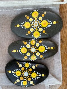 three black rocks with yellow and white designs on them