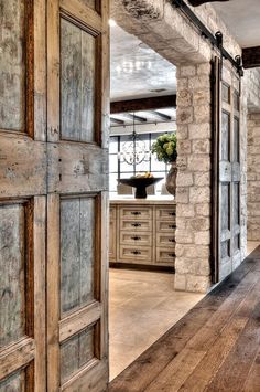 an open door leading to a kitchen and dining room with stone walls, wood floors and exposed beams