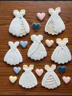 decorated cookies in the shape of wedding gowns and dresses on a wooden table with hearts