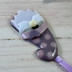 a purple and white toothbrush sitting on top of a wooden table next to an object