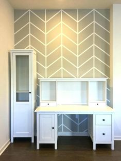 a white desk and cabinet in front of a wall with an arrow pattern painted on it