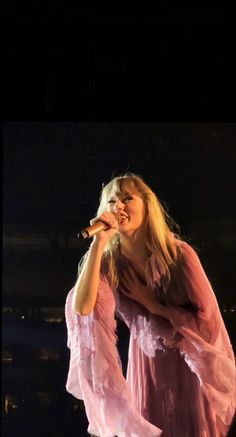 a woman standing on top of a stage holding a microphone in her hand and singing