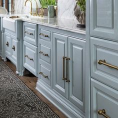 a kitchen with marble counter tops and gold pulls on the cabinets, along with potted plants