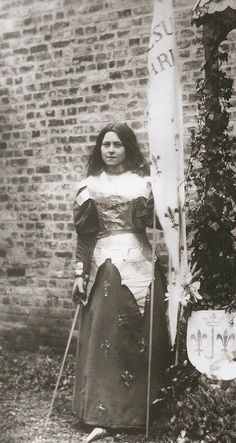 an old black and white photo of a woman with skis in front of a brick wall