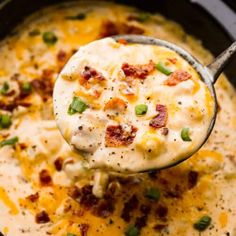 a ladle full of cheesy potato soup with bacon and green onions