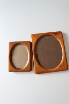 two wooden frames sitting next to each other on a white surface, one has a mirror in the middle