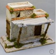 a miniature house made out of clay with moss growing on the roof