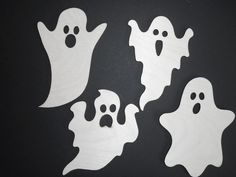 four white ghost cutouts on a black background