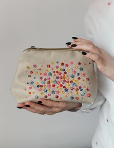 a woman's hand holding a purse with colorful flowers on it