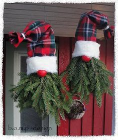 two christmas wreaths hanging from the side of a red door with plaid hats on them