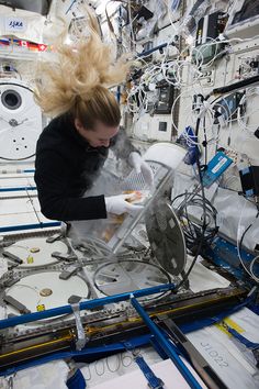 a woman in black jacket and white gloves working on an assembly line with lots of wires