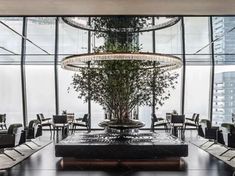 an indoor dining area with tables, chairs and a tree in the center surrounded by glass walls